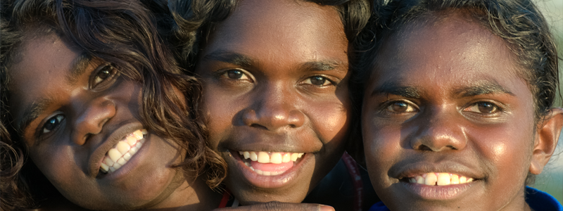 Three young Aboriginal children smiling at camera