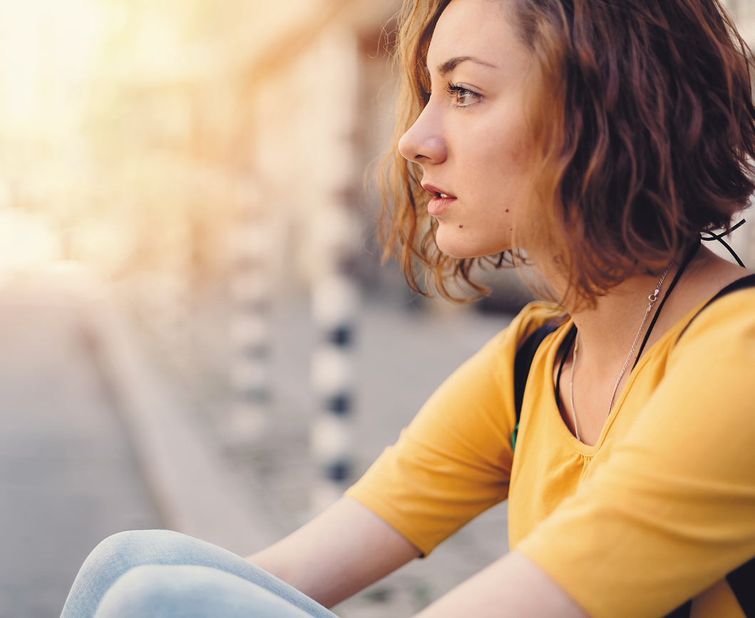 Teenage girl sitting profile looking towards sun