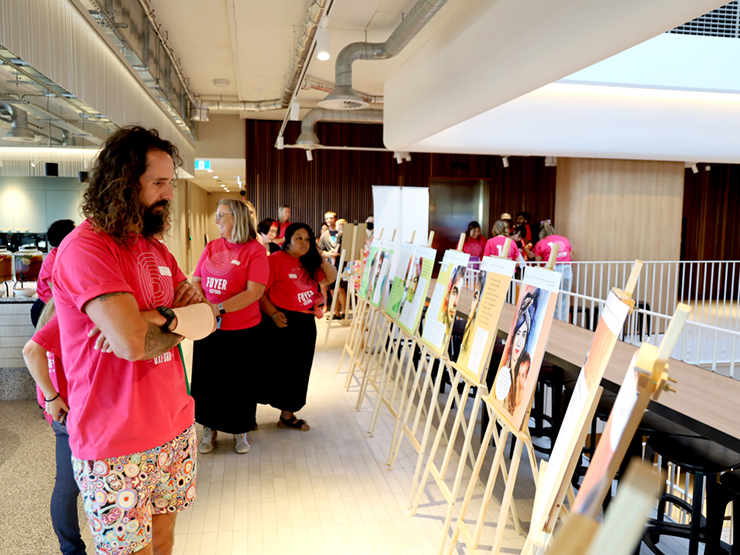 People standing looking and reading large graphic boards that are resting on easels at a corporate event.
