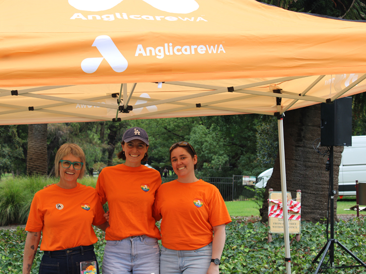 Three Anglicare WA workers standing under a gazebo smiling at the camera.