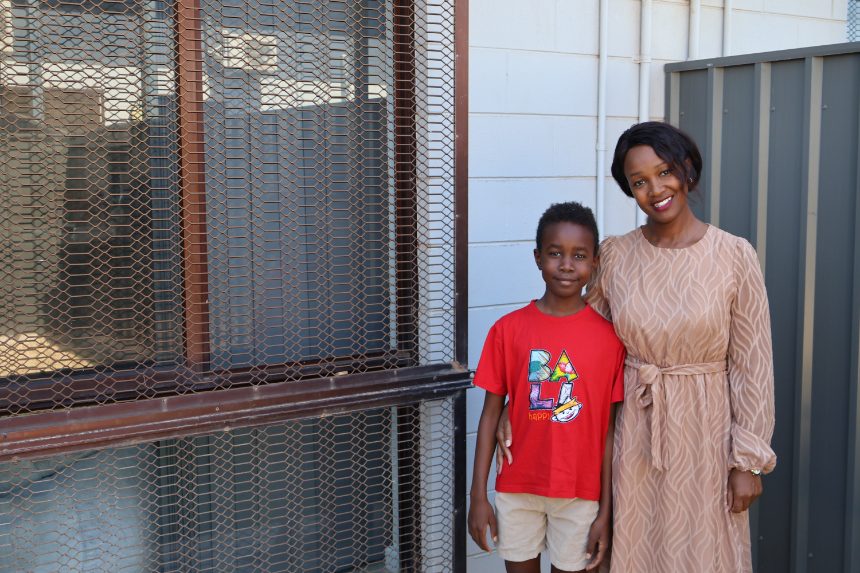 Mother and young son stand side-by-side outside their Pilbara home.
