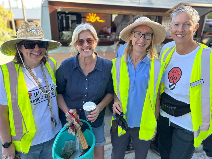 A group of four women standing in gardening clothes smiling at the camera