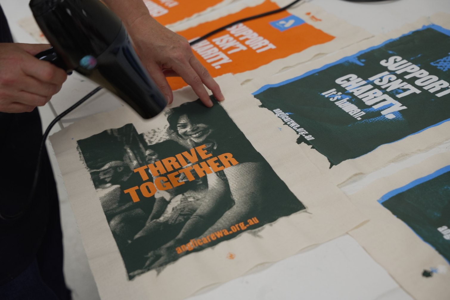The final canvas prints of the Thrive Together Campaign being finished with a hair dryer.