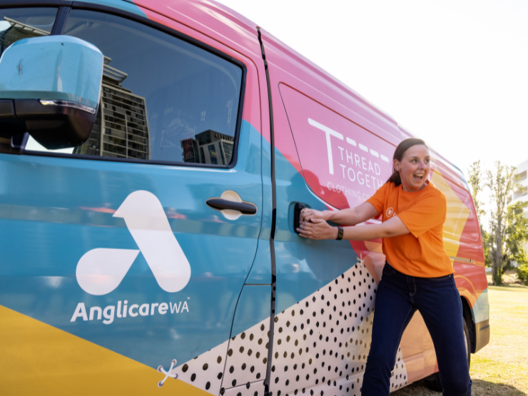 Lady pulling open the door to a brightly decorated minivan with Thread Together and Anglicare WA logo on it.
