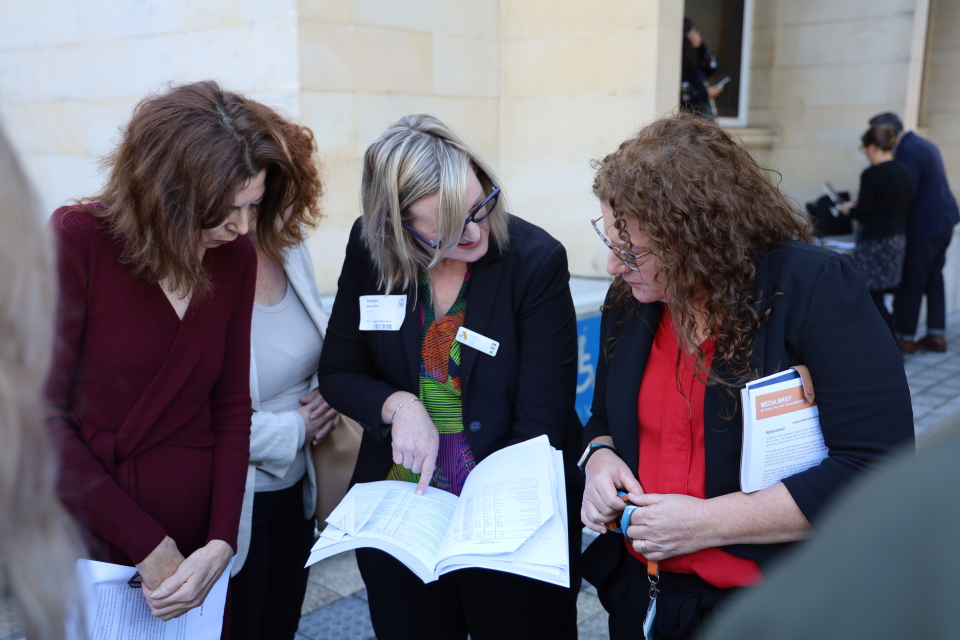 Anglicare WA executives standing outside looking over report. 