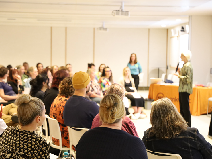 A group of people sitting looking toward a presenter who is talking