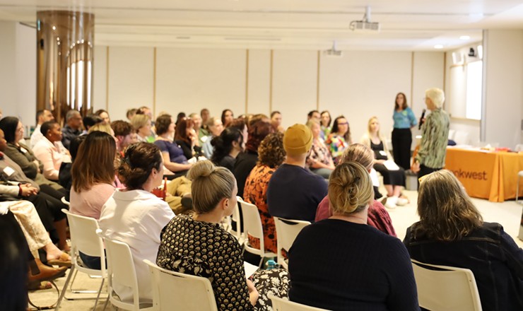 A large group of people sitting watching a presenter speak