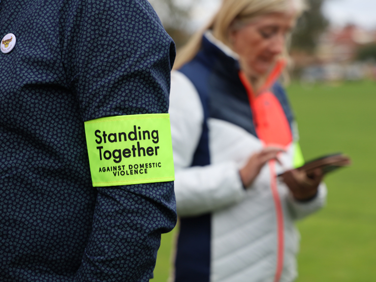 A man wearing an arm band that says, 'Standing Together Against Domestic Violence'.