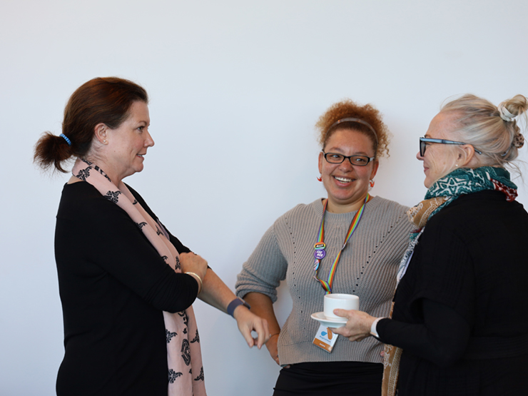 A group of ladies (colleagues) who are standing and talking to each other.