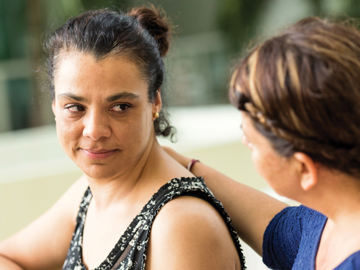 A woman is speaking to another woman, both displaying expressions of engagement and connection during their conversation