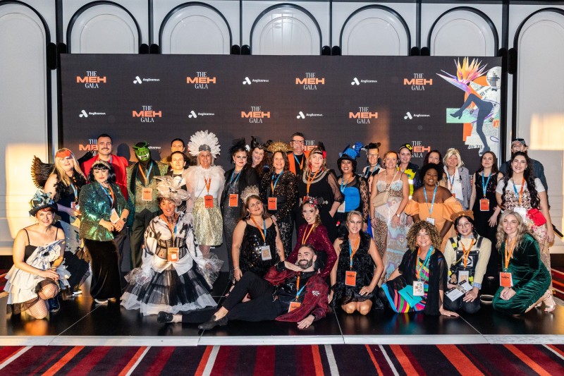 A group of 31 Anglicare WA volunteers at MEH Gala, dressed in glamorous and flamboyant costumes.