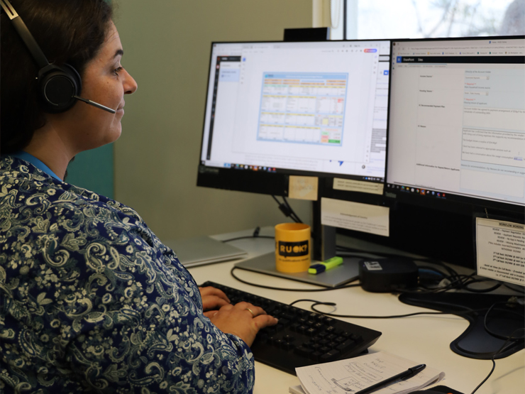 An image of a lady's face who is sitting looking at her computer screen, she is wearing a headset that is for phone calls.
