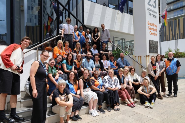 A large crowd of Anglicare WA workers sitting on the steps outside the East Perth office building. 