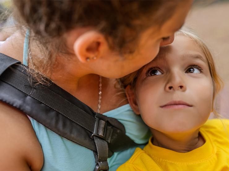 An adult leans in to kiss a young child on the forehead
