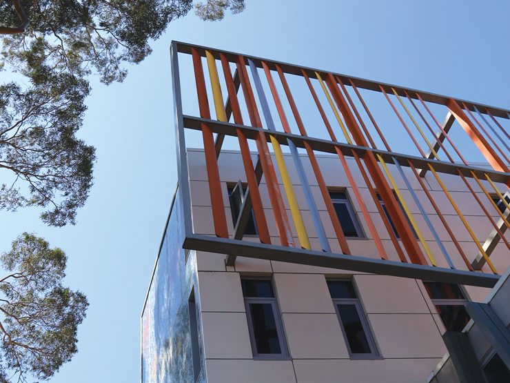 A building featuring a metal frame is set against a backdrop of a tree