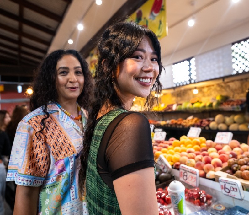 Two women buying fresh fruit at the local market 