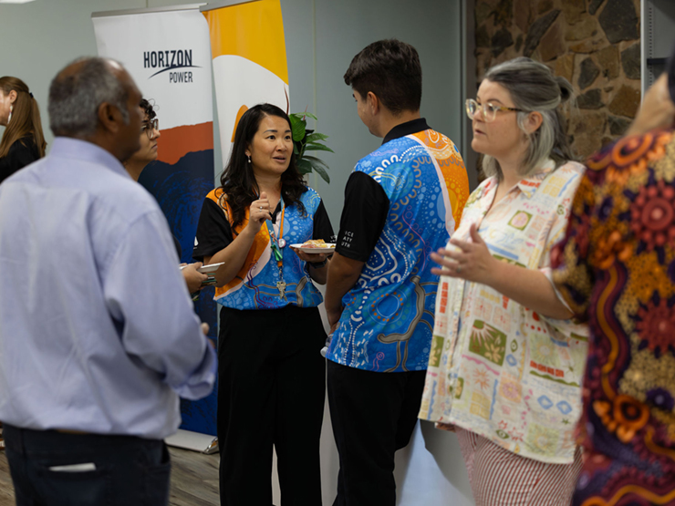 Two Anglicare WA workers standing talking to each other at a corporate event.