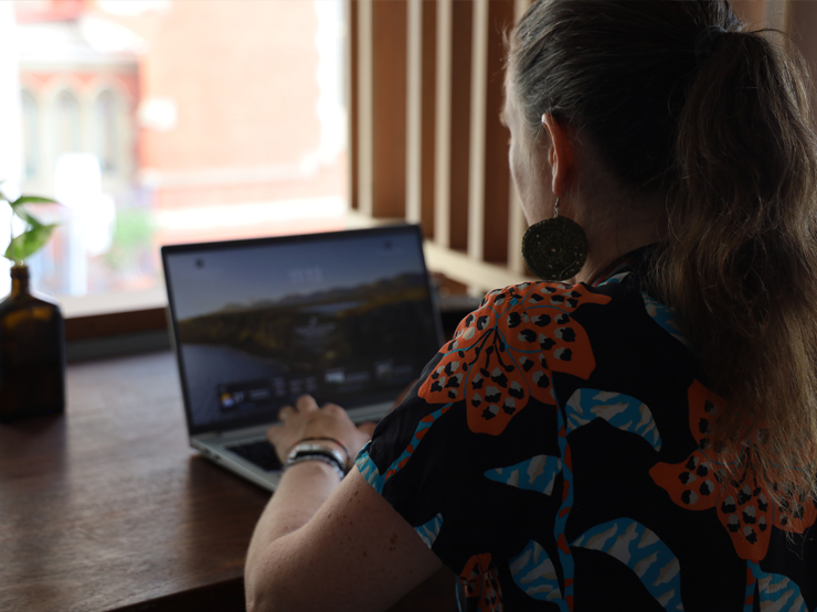 A close up shot of a person sitting at a laptop at a coffee shot