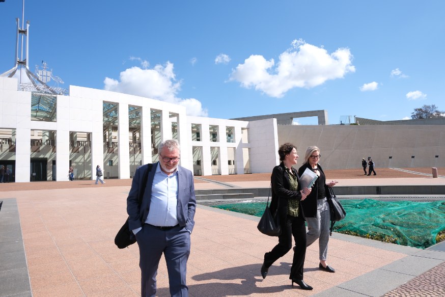Mark Glasson and Sarah Kane walking away from Parliament House smiling.