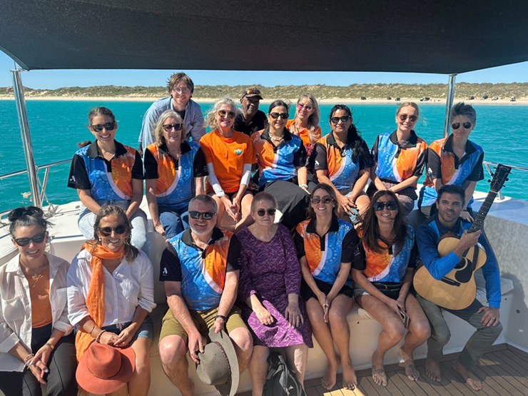 A group of Anglicare WA employees who are sitting together for a group picture on a boat off the coast.