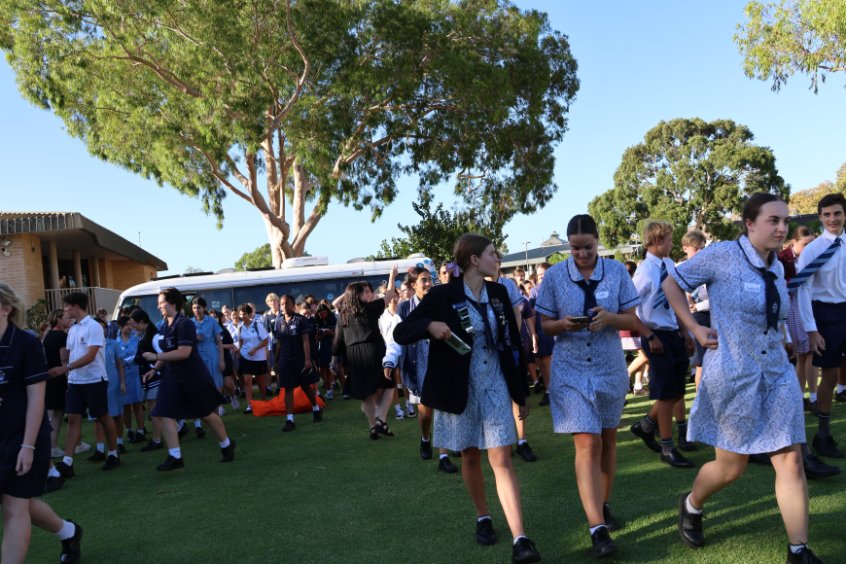 A candid outdoor photo of a large crowd of students smiling and talking, walking casually in various directions. 