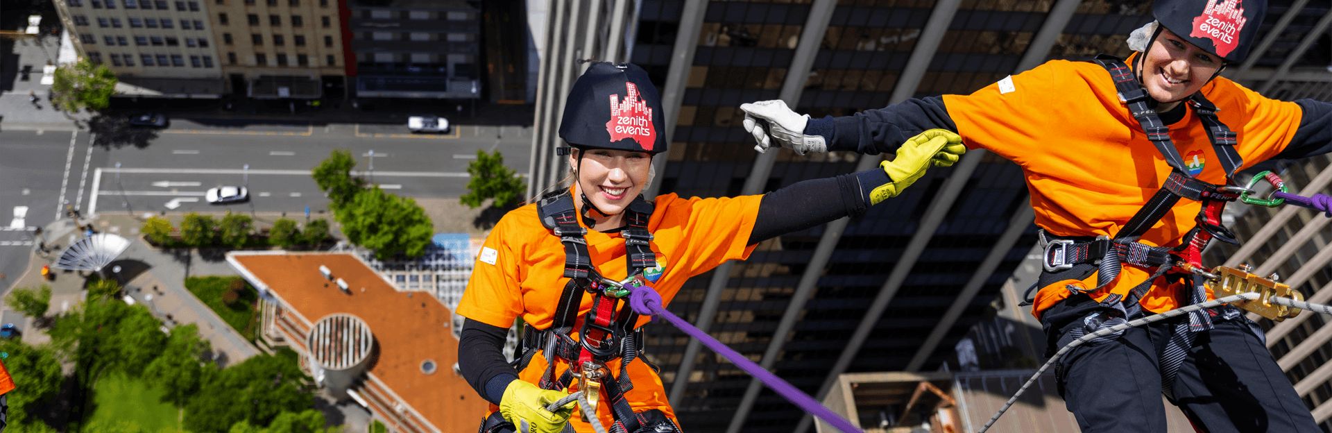 Photo of Two Anglicare WA workers abseiling from a tall building in Perth City.