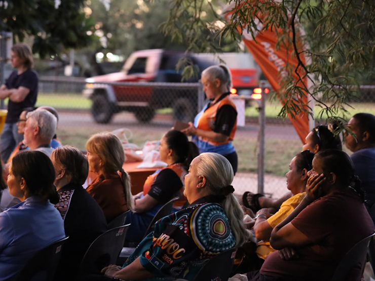 A group of people sitting at an event looking toward something out of shot.