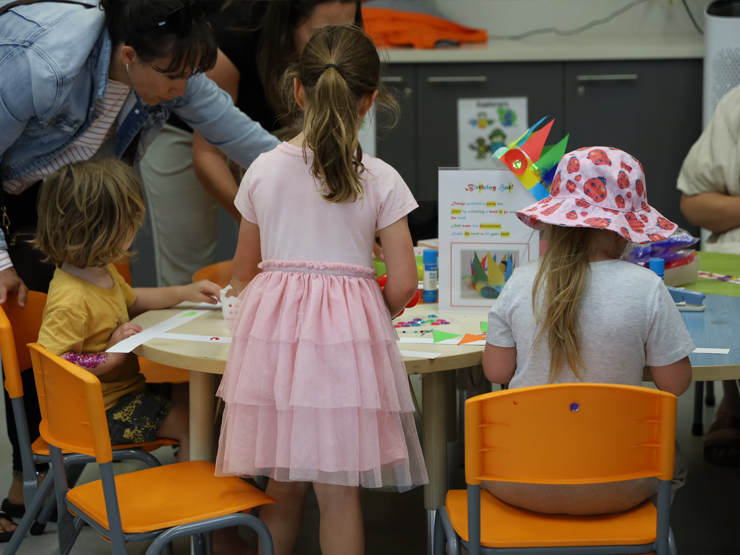 A group of children sitting at a desk doing arts and crafts.