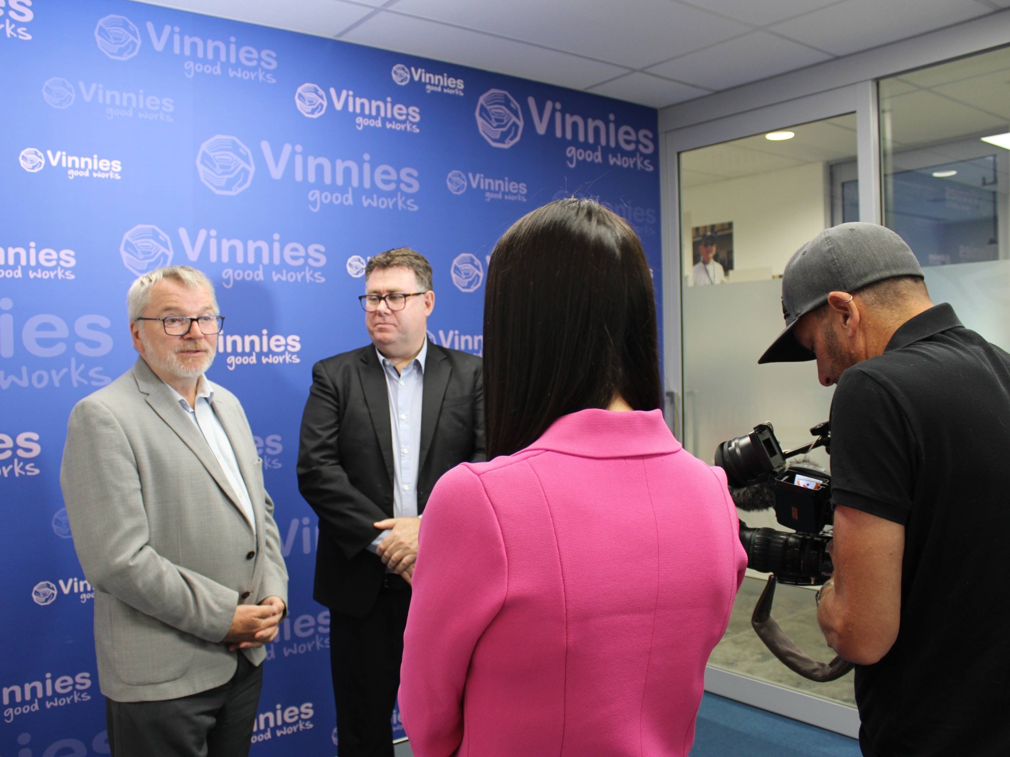Anglicare WA CEO Mark Glasson and Vinnies WA Executive Manager Andrew York stand in front of a Vinnies branded backdrop as they address the media. 