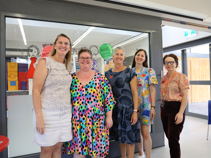 A group of 5 women standing smiling at the camera in a early learning centre