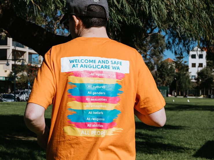 A person whose shirt says welcome and safe at Anglicare WA - all ages, all sexes, all cultures, all genders, all sexualities, all ethnicities, all beliefs, all religions, all abilities, all people.