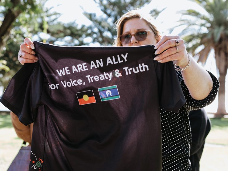 Person holding up a shirt with 'We are an Ally for Voice, Treaty and Truth' 