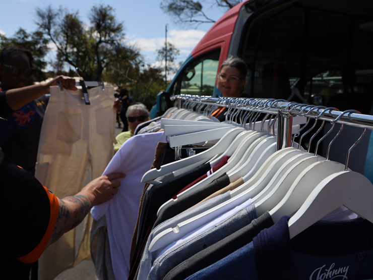 A rack of clothing with a person reaching out to look at an item.