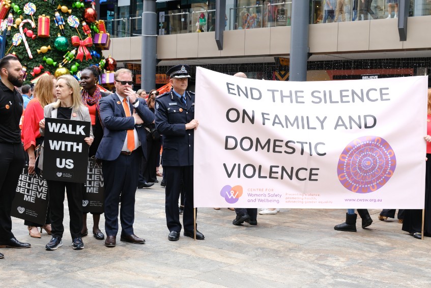 A photo of the Assistant Police Commissioner holding a banner which reads" End the silence on family and domestic violence".