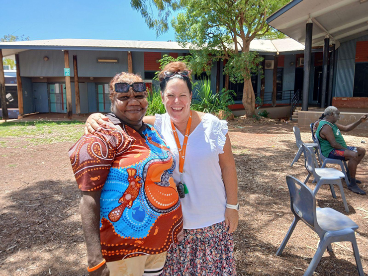 Two women standing together smiling for the camera at a community event.