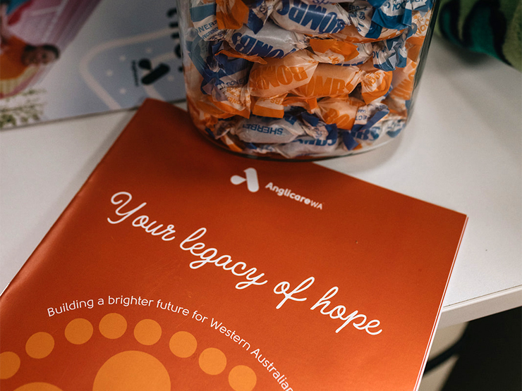 Bequests. Image of a booklet with the text 'Your legacy of hope' written on the front sitting on a white table with blue and orange lollies.