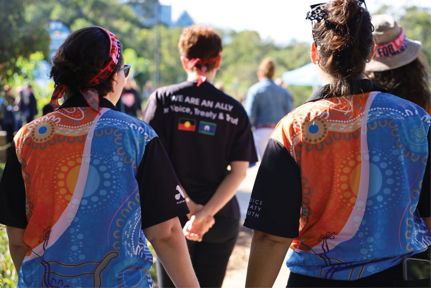A group Anglicare WA staff walking, all of which are wearing shirts with Aboriginal art designs on them.