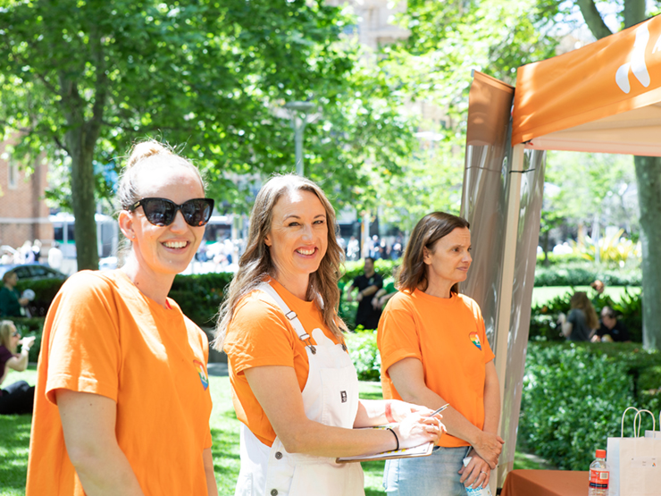 Three Anglicare WA workers standing looking at the camera from the side smiling.