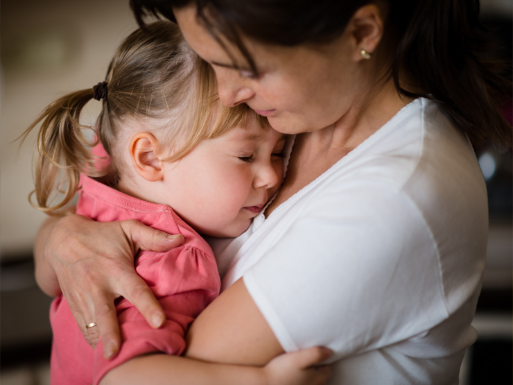A woman embraces a little girl, conveying warmth and affection in a tender moment.