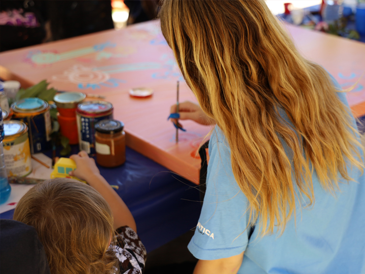Young person and a child painting on a canvas together.